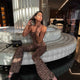 A woman sitting in a strapless animal print jumpsuit and black shoes